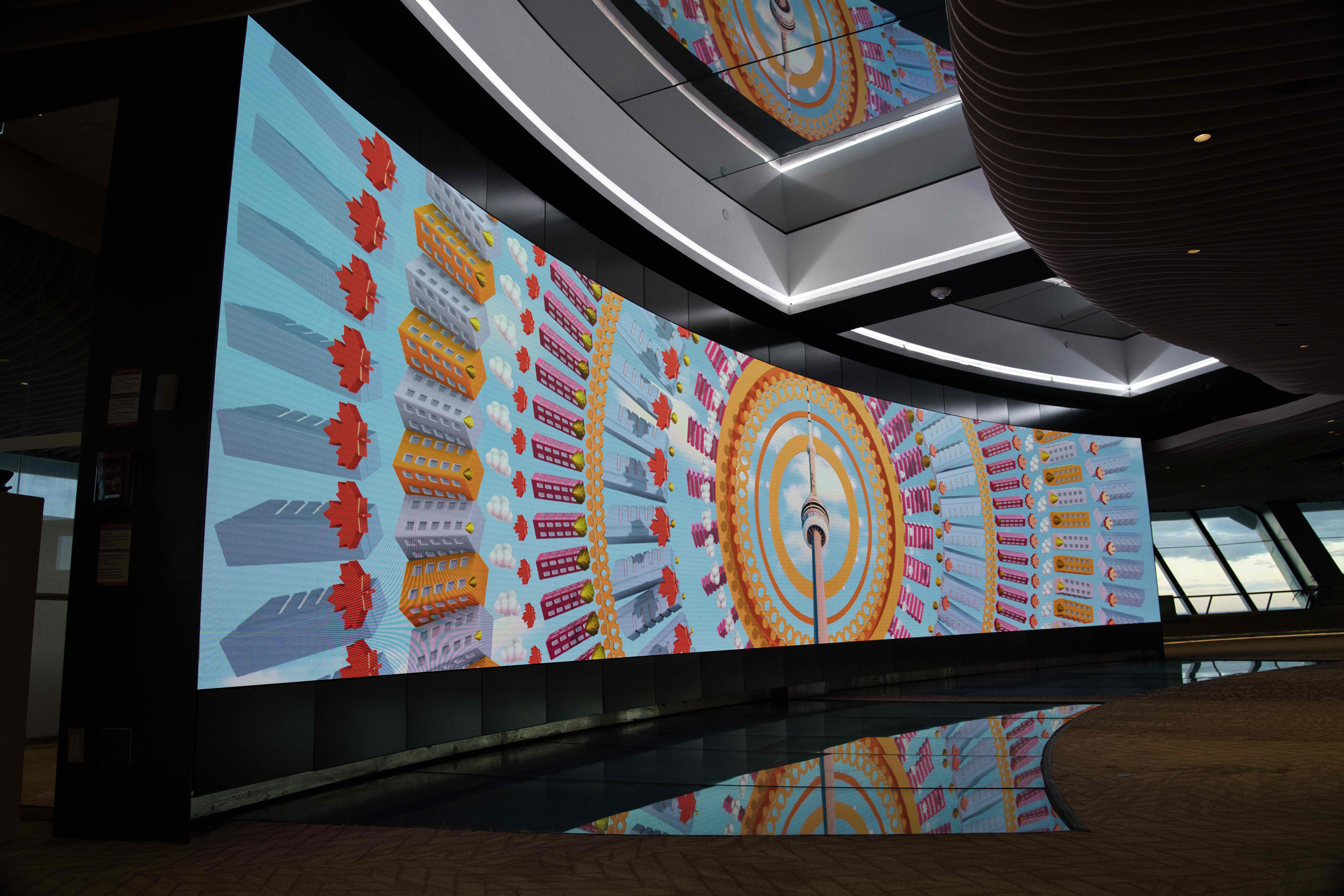 Curved video wall showing a kaleidoscope of red maple leaves and colourful blocks radiating from the CN Tower