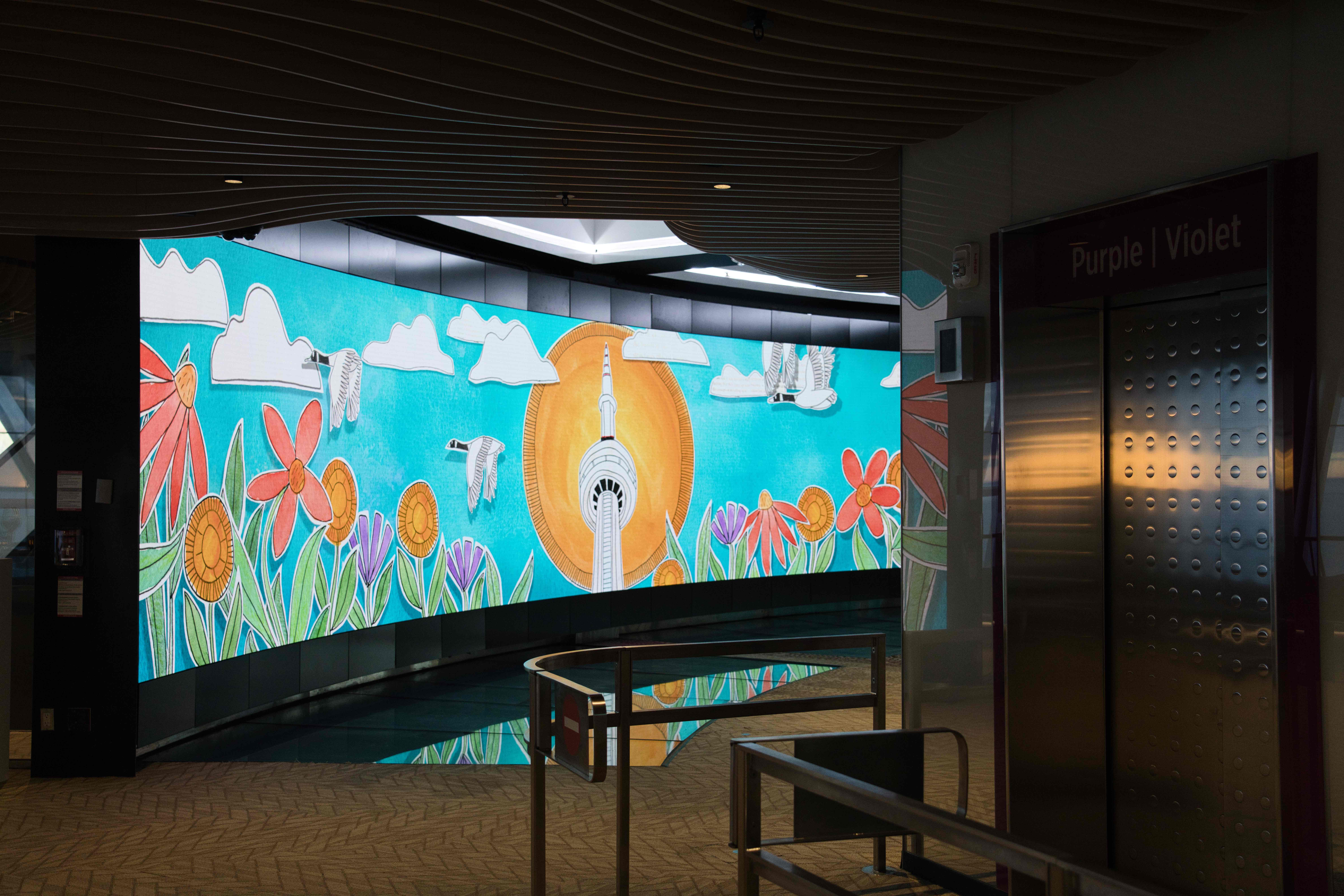 The illustrated flowers-and-sun scene on the video wall, seen from beside the elevators