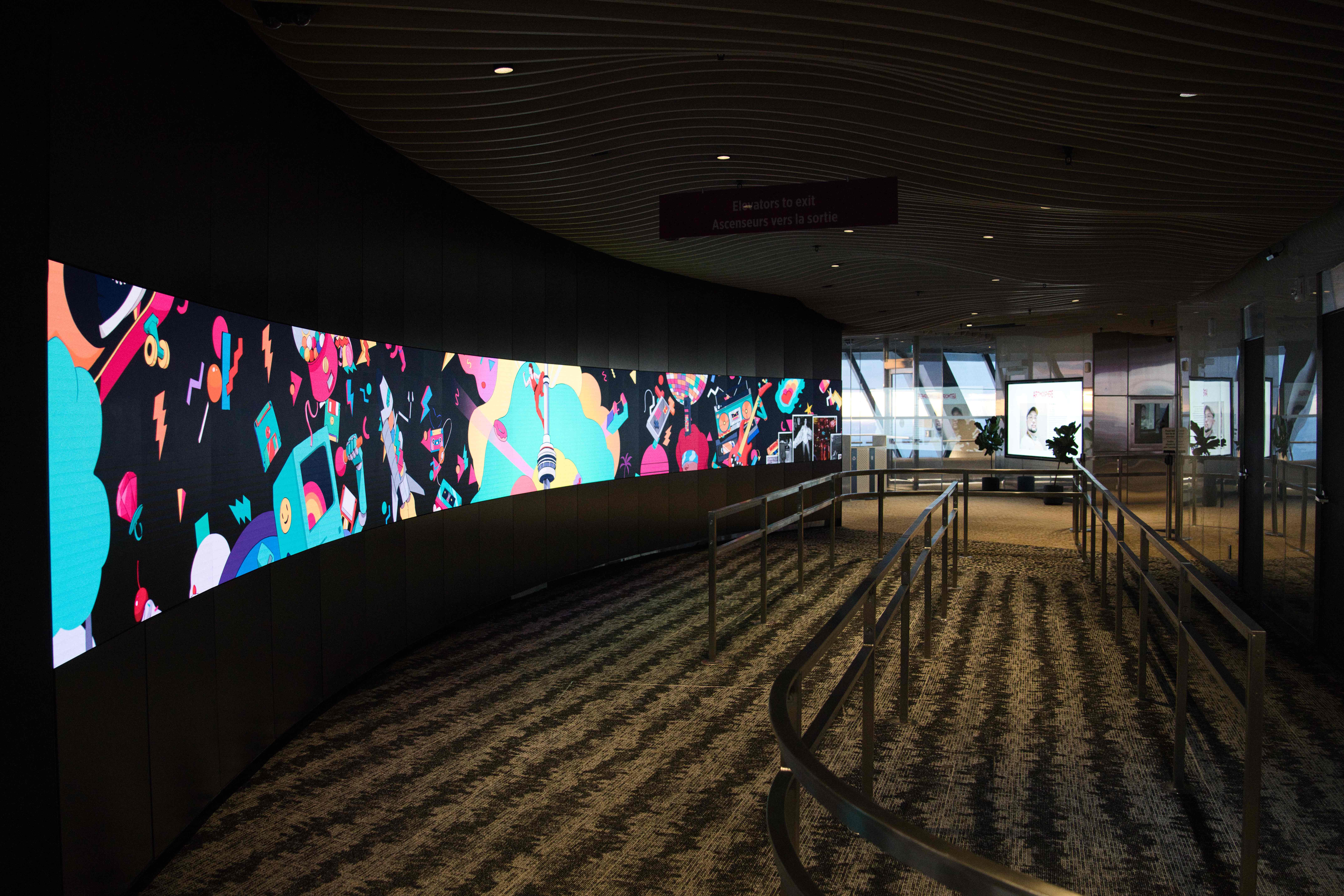 Long curved video wall playing the pop-art animation beside a railed visitor walkway