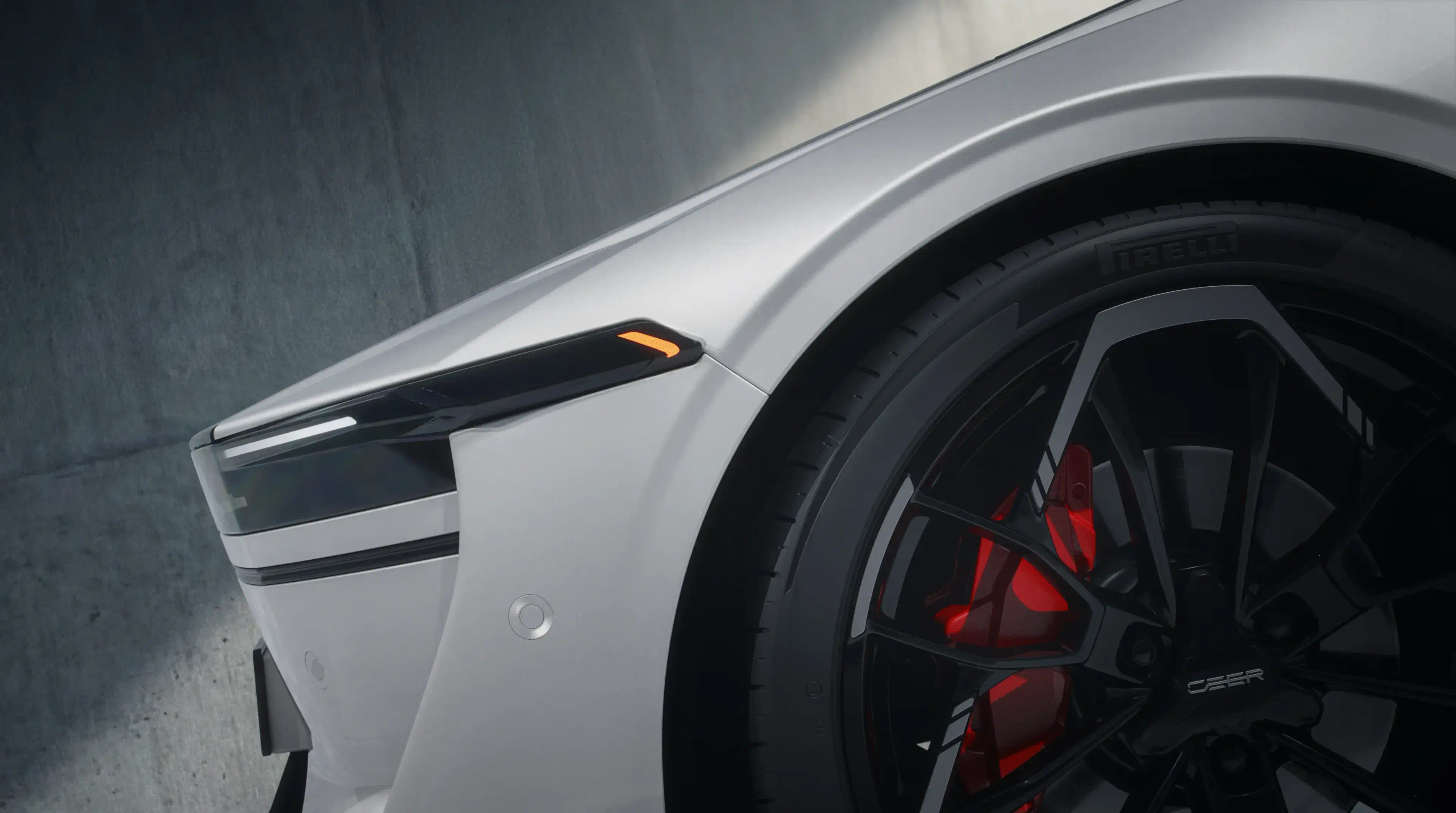 Front corner of a white CEER car: a slim headlight with an amber accent above a black wheel and red brake caliper