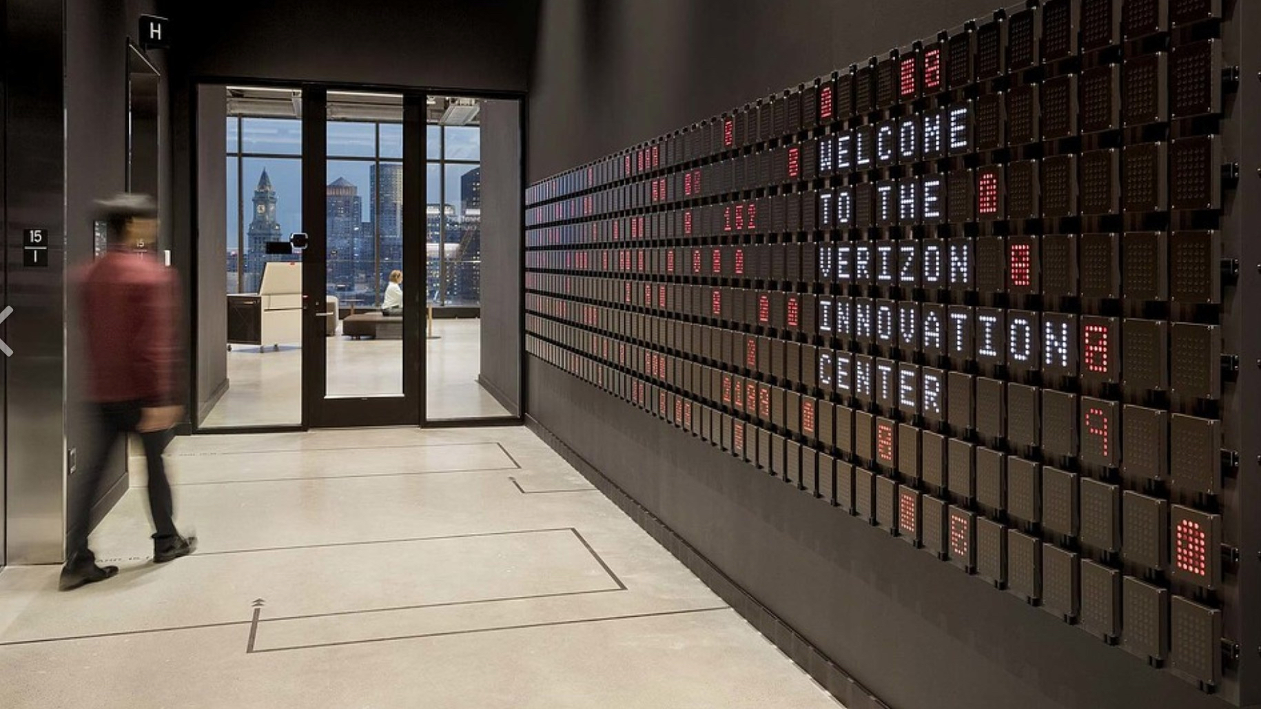 A visitor passes the screen wall at Verizon's Boston headquarters as it spells Welcome to the Verizon Innovation Center
