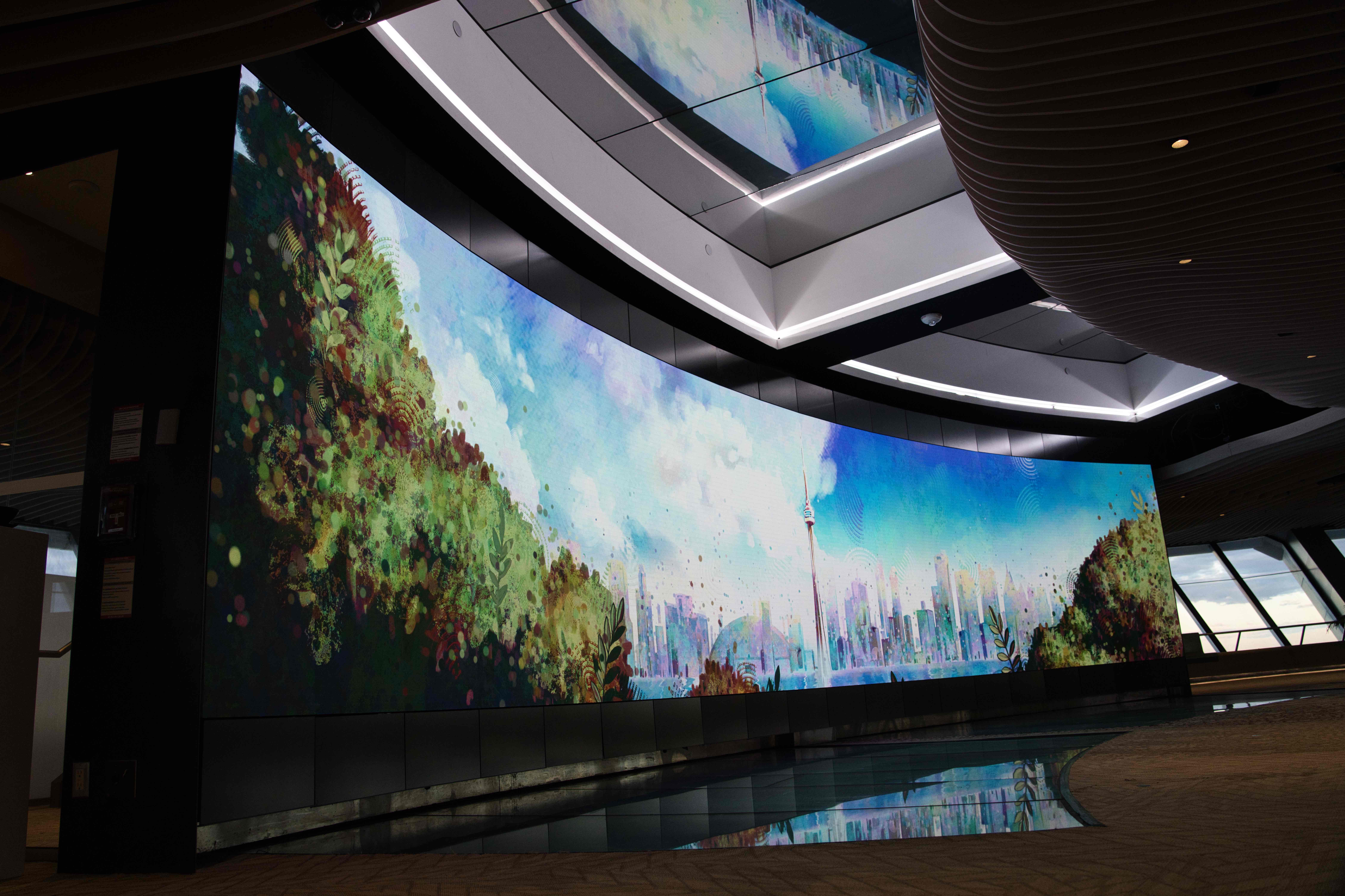 Curved video wall showing a painterly Toronto skyline and CN Tower framed by trees, reflected in the floor