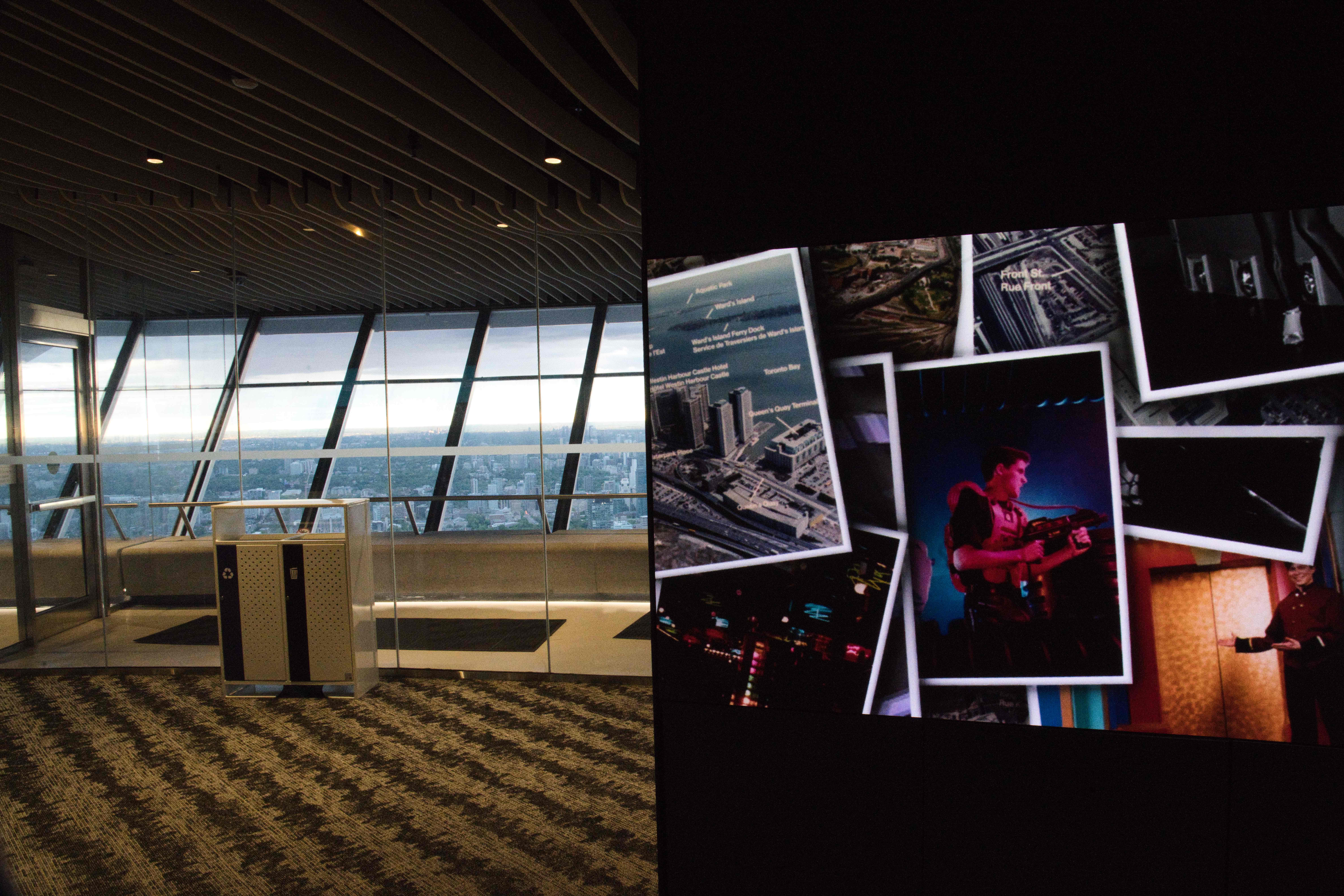 Collage of archival photos on a dark display beside floor-to-ceiling windows overlooking the city