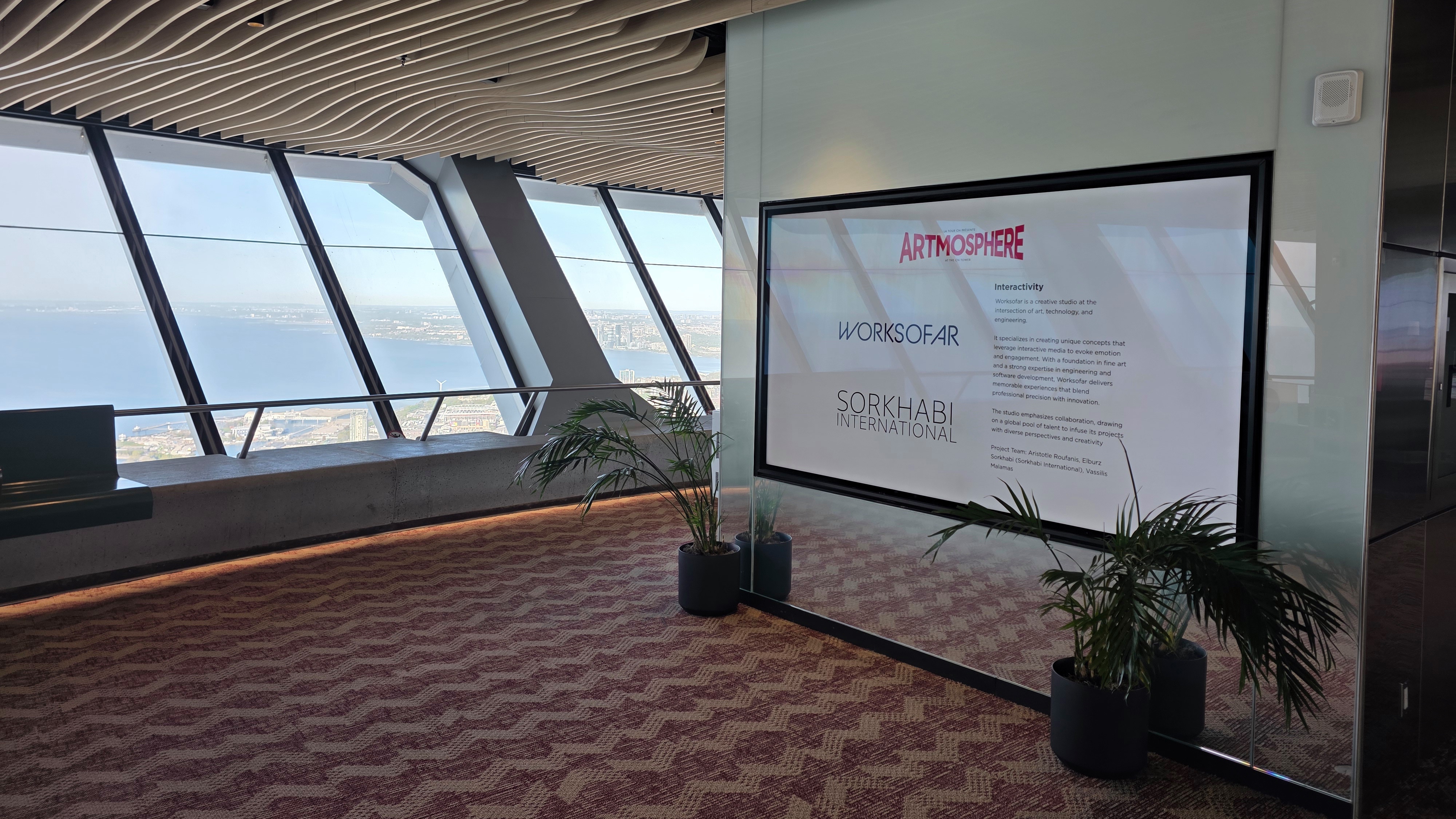 Screen crediting Artmosphere, Worksofar and Sorkhabi International beside windows overlooking the water