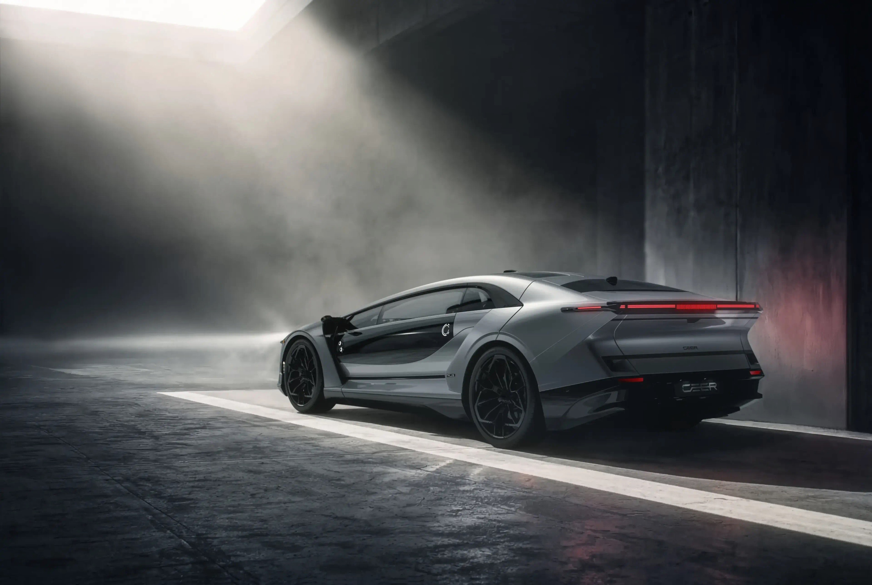 A silver CEER sedan in a misty concrete hall, its red rear light signature glowing under a shaft of daylight
