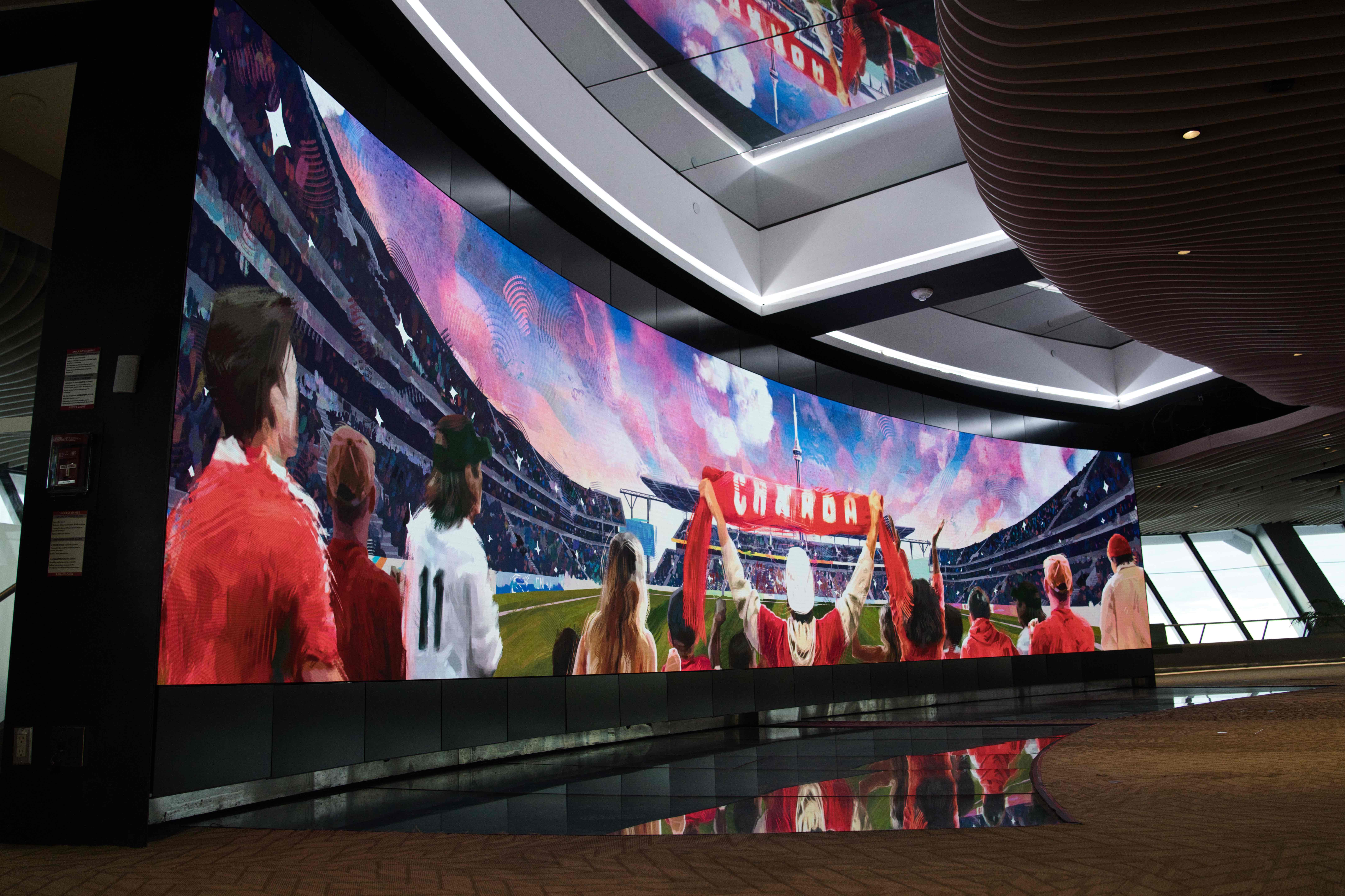 Curved video wall showing an illustrated stadium crowd in red, with a fan holding up a Canada scarf
