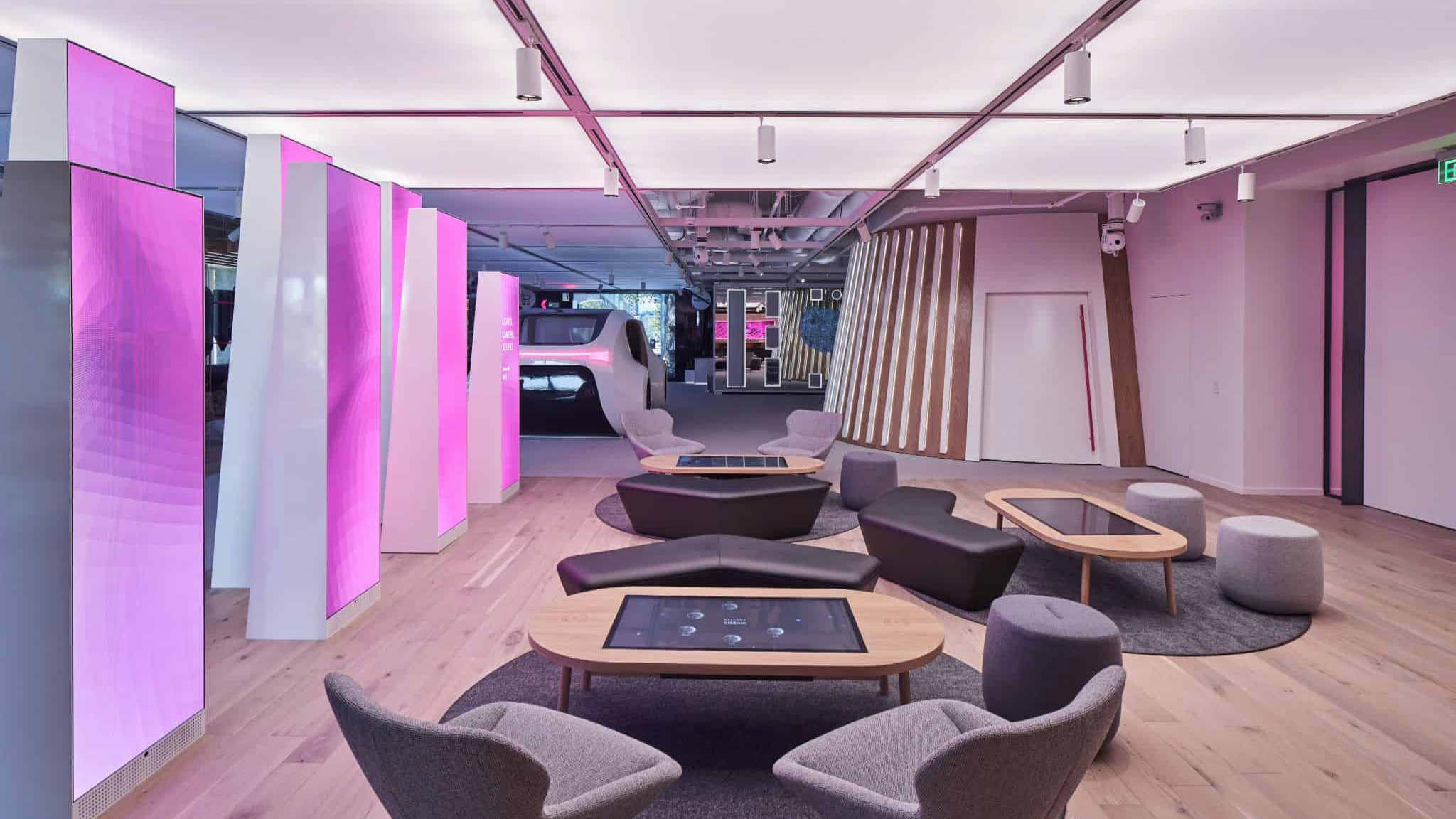 Lounge at the T-Mobile 5G & Me Innovation Center, with magenta-lit columns and tables with built-in screens