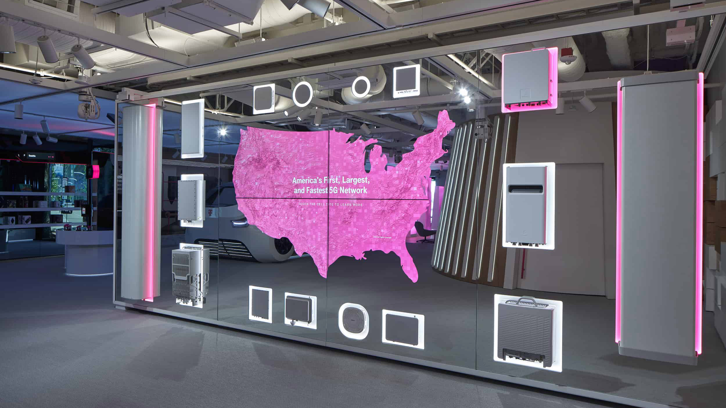 Display wall with a magenta map of the US, framed by illuminated mounts holding 5G network hardware