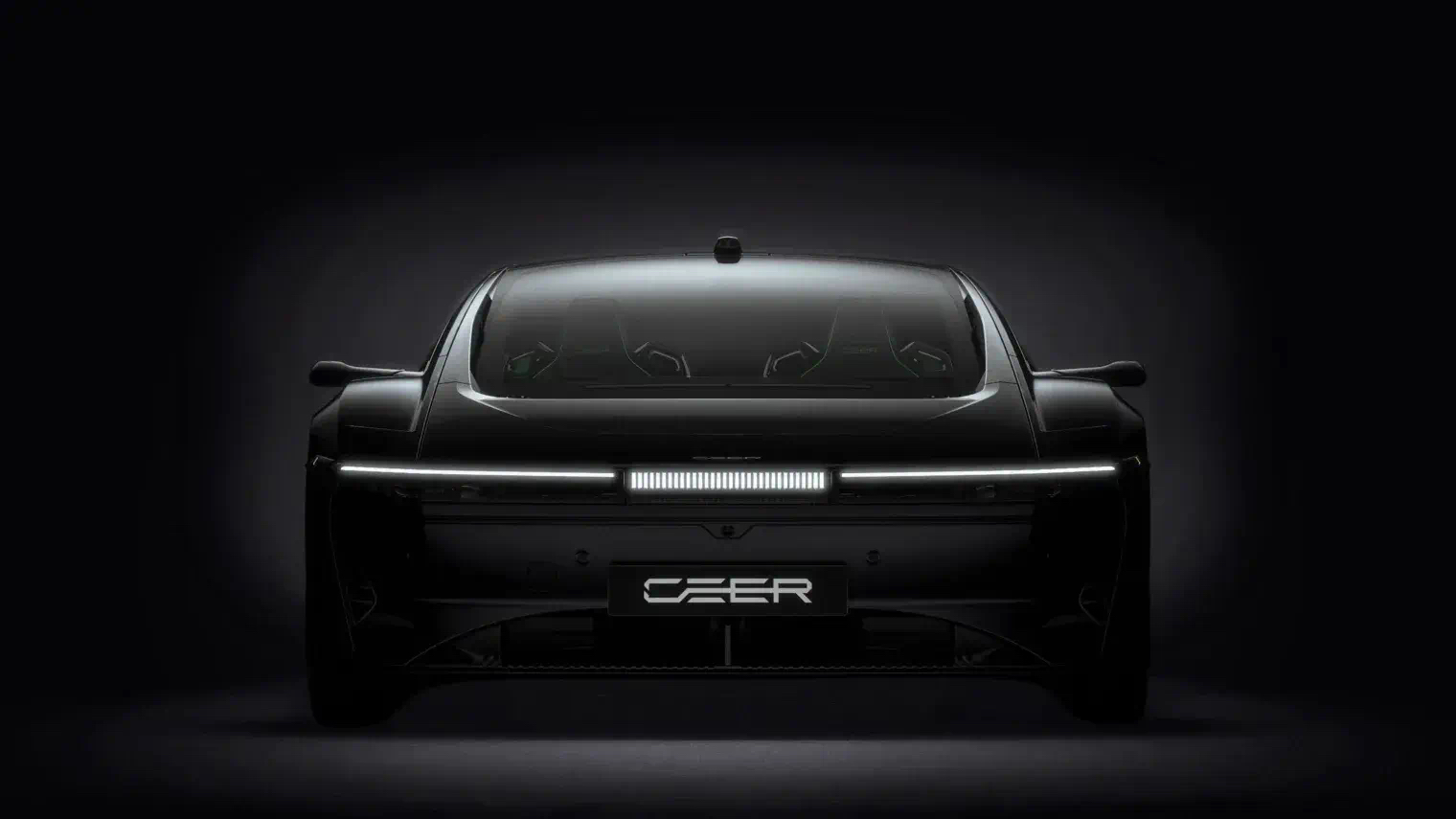 Front view of a dark CEER car in a black studio, its white front light bar lit across the nose